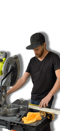 a man cutting a piece of wood with a circular saw